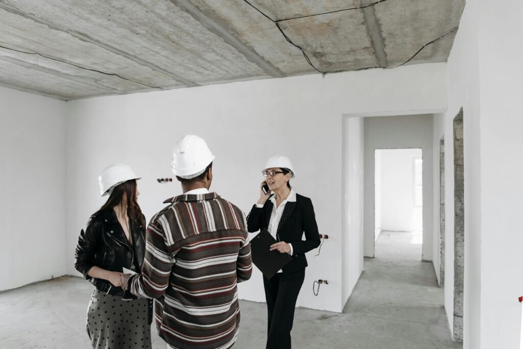 Real estate agent discussing with clients inside an empty property under construction.