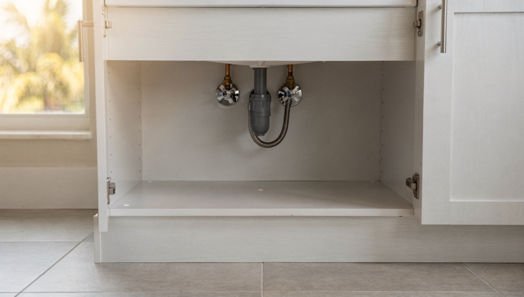 Under-sink plumbing connections and shutoff valves in a South Florida rental property during a scheduled turnover inspection